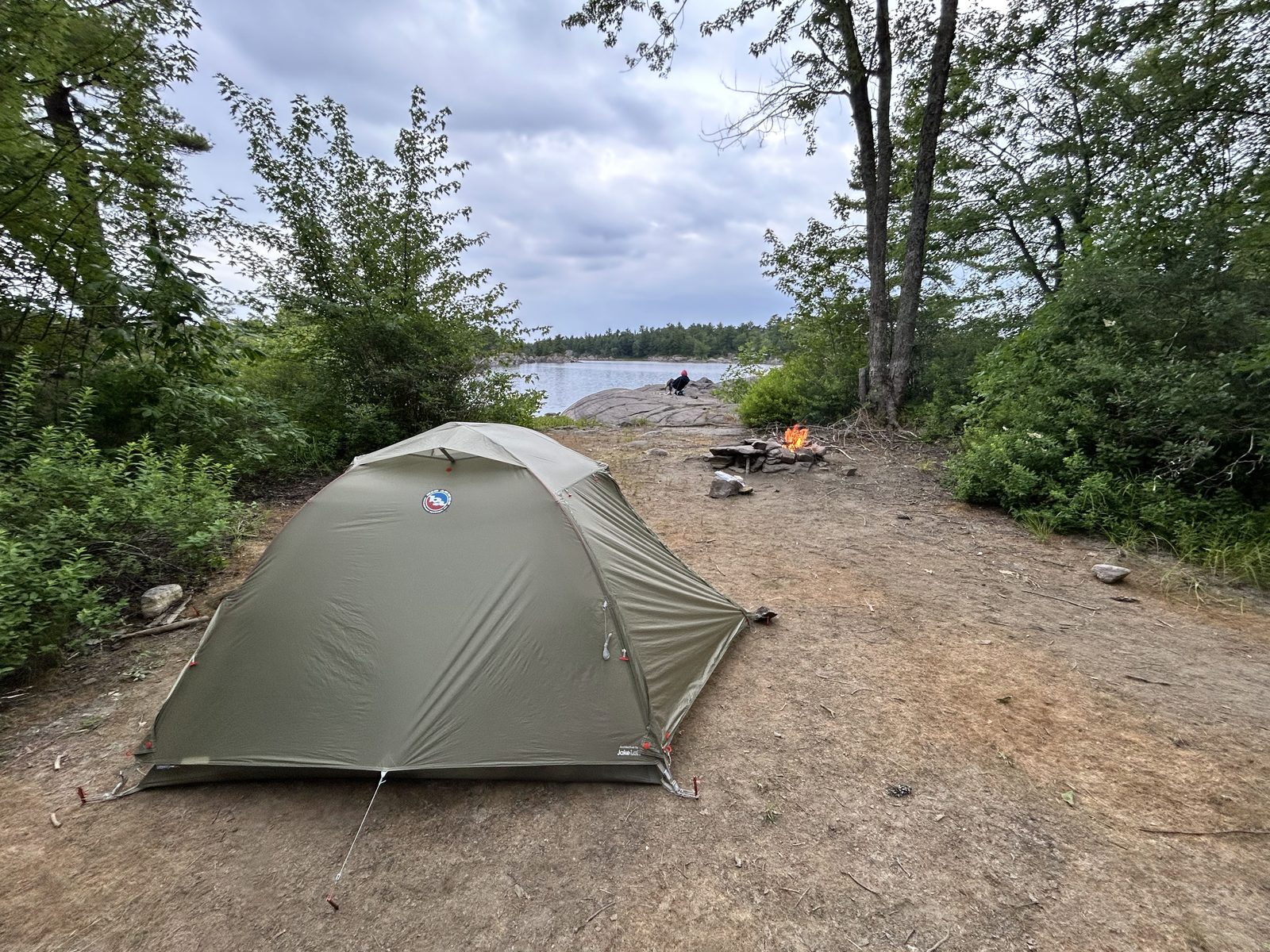A tent pitched on the flat ground at site 647 with a fire pit and the French River behind