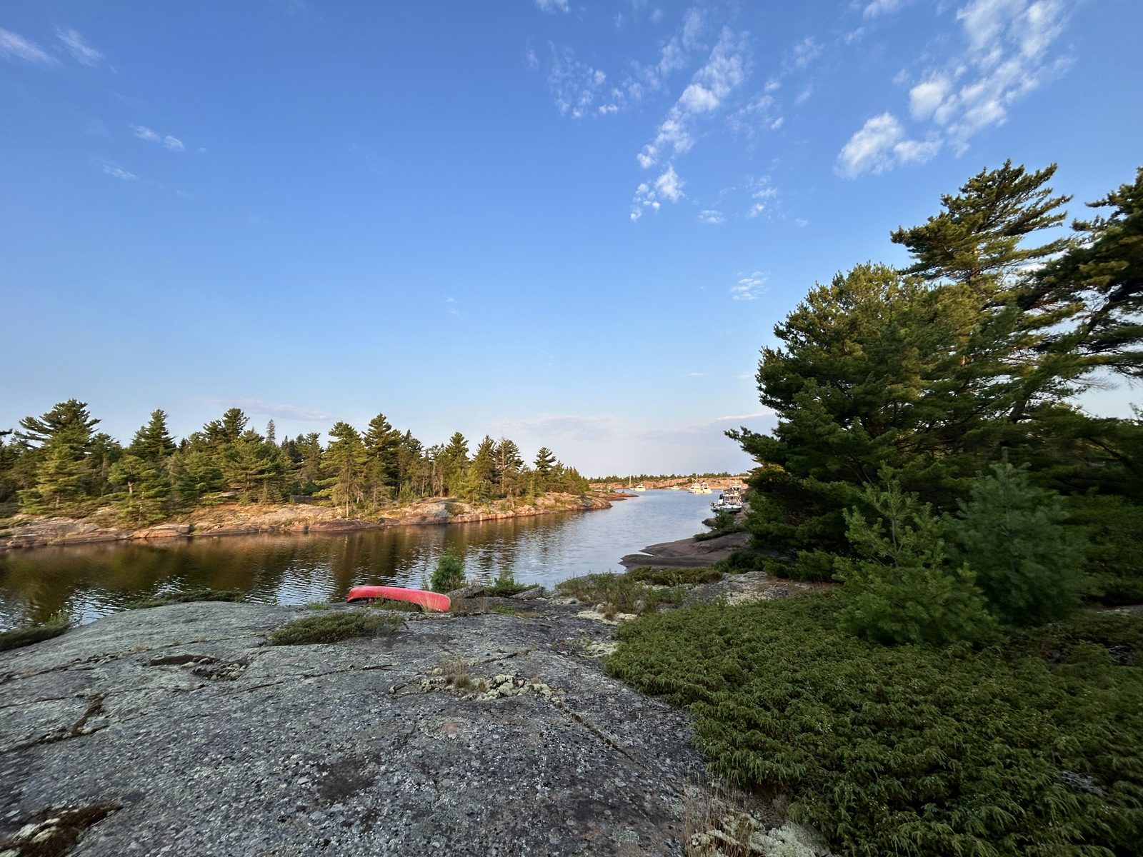 Campsite 812 on an exposed slab of granite, with a red canoe at the shore and boats in the bay beyond