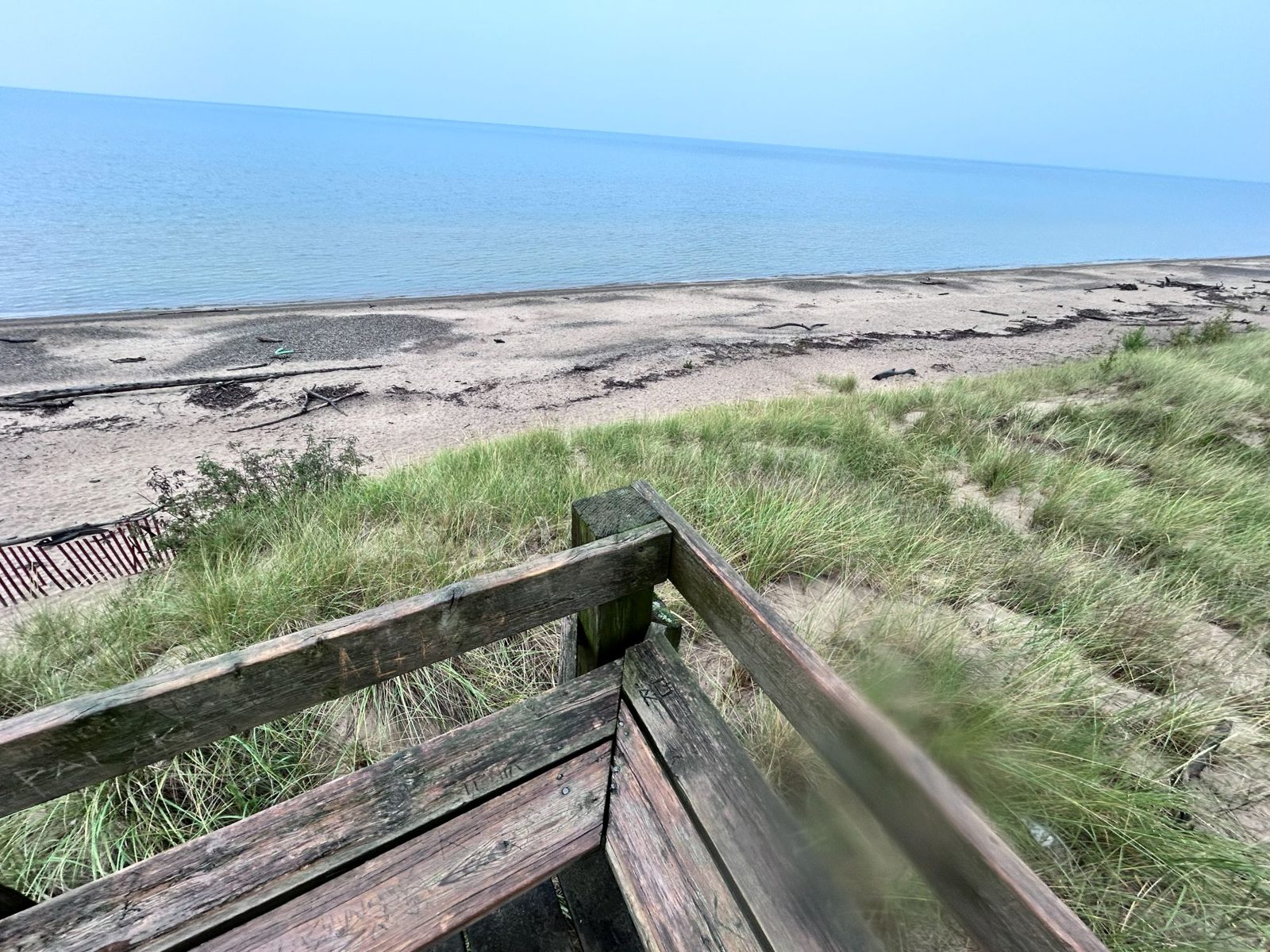 Weathered wooden stairs descending through marram grass on the dune ridge to the Pinery beach and Lake Huron