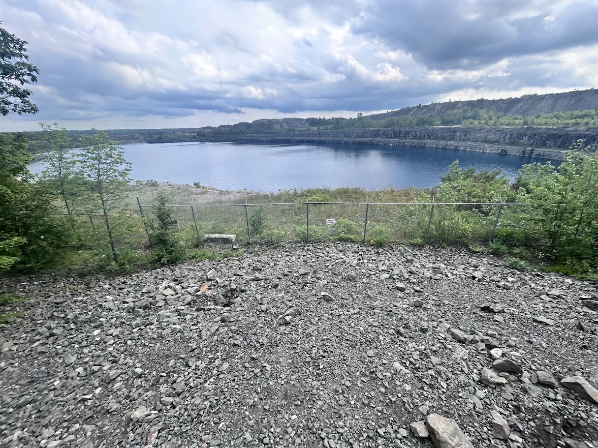 Turquoise water in the flooded open-pit Marmora Mine, viewed from a gravel overlook